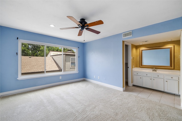 unfurnished bedroom featuring light carpet, ensuite bathroom, and ceiling fan