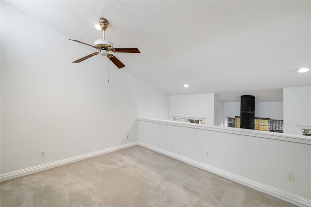 spare room featuring ceiling fan, light colored carpet, and lofted ceiling