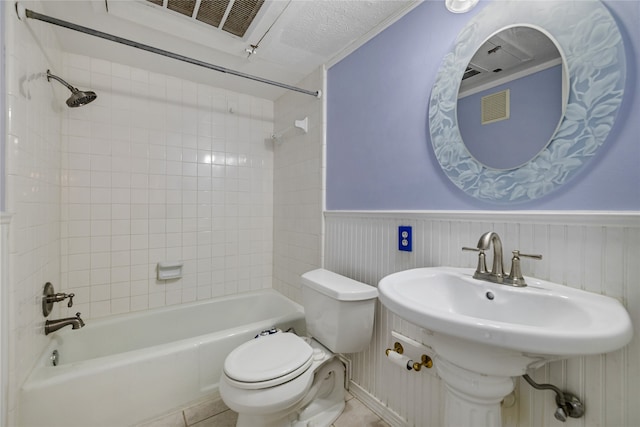 bathroom featuring tile patterned flooring, tiled shower / bath combo, and toilet