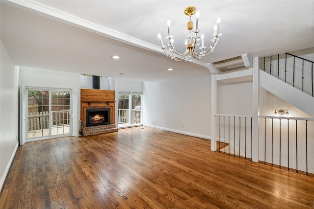 unfurnished living room with beam ceiling, a wealth of natural light, a notable chandelier, and hardwood / wood-style flooring