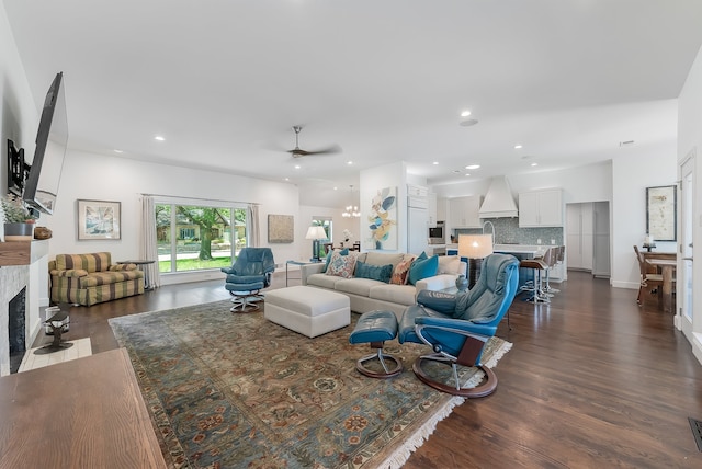 living room featuring ceiling fan, dark wood-type flooring, and a tiled fireplace