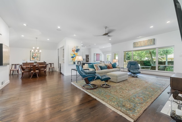 living room with ceiling fan with notable chandelier, vaulted ceiling, and dark wood-type flooring