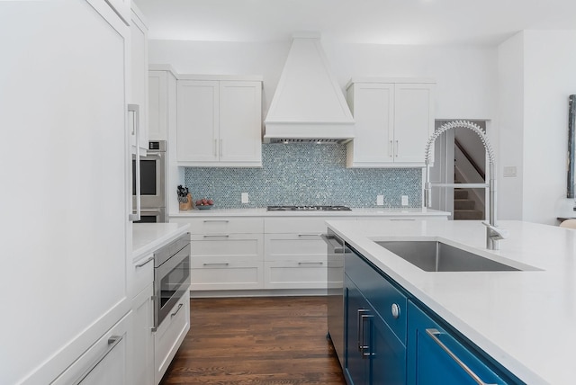 kitchen with blue cabinets, dishwasher, dark hardwood / wood-style floors, lofted ceiling, and an island with sink