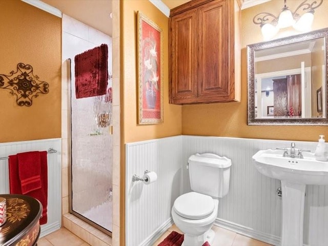 bathroom with tile patterned flooring, toilet, a shower with shower door, and ornamental molding