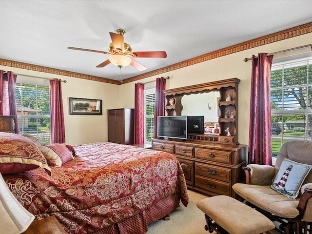 carpeted bedroom featuring multiple windows, ceiling fan, and crown molding