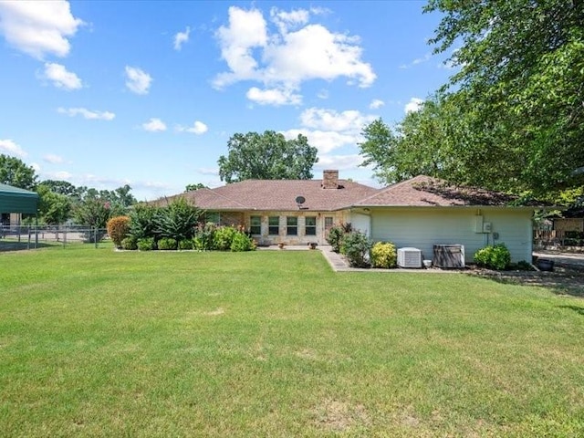 rear view of property featuring central air condition unit and a yard