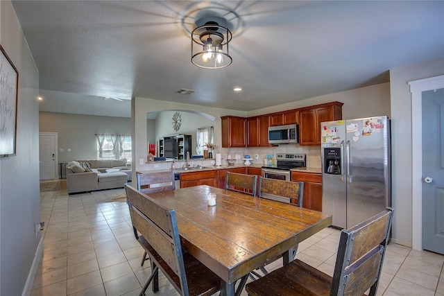 kitchen with sink, decorative backsplash, light tile patterned floors, appliances with stainless steel finishes, and kitchen peninsula