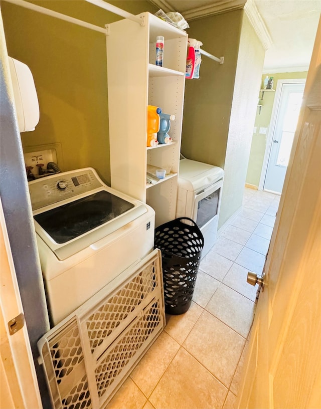 clothes washing area with light tile patterned floors, washer / clothes dryer, and crown molding