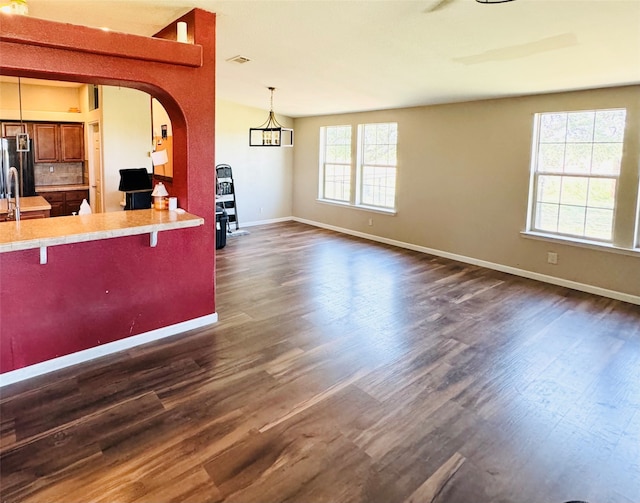 kitchen featuring a healthy amount of sunlight, dark hardwood / wood-style flooring, stainless steel fridge, pendant lighting, and a breakfast bar area