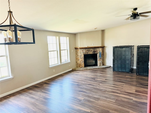 unfurnished living room with a stone fireplace, ceiling fan, and dark hardwood / wood-style floors