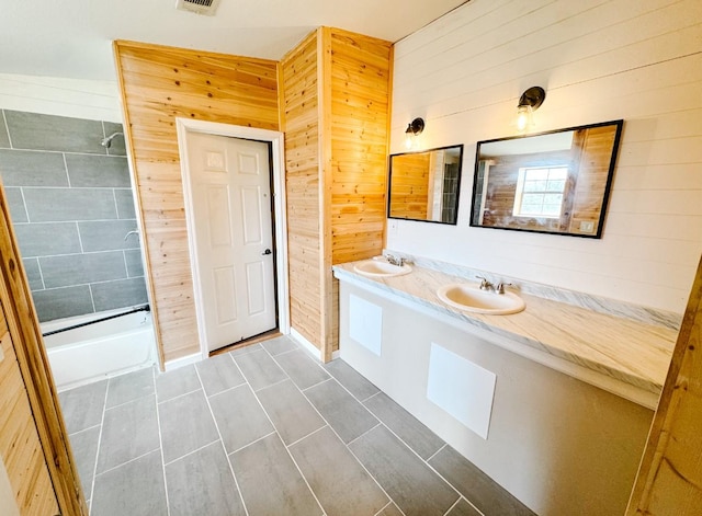 bathroom featuring double vanity, visible vents, wood walls, and a sink