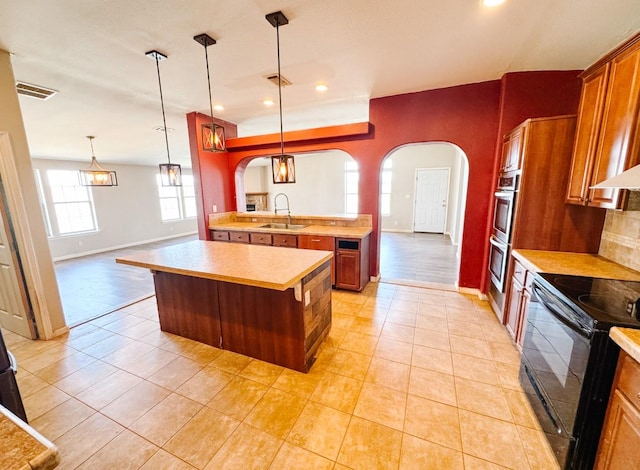 kitchen featuring a sink, electric range, arched walkways, and light countertops