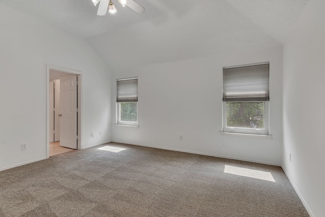 empty room featuring ceiling fan, light colored carpet, lofted ceiling, and a textured ceiling