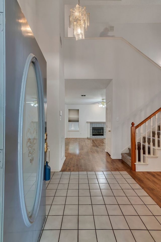 foyer with a tile fireplace, light hardwood / wood-style flooring, and ceiling fan with notable chandelier