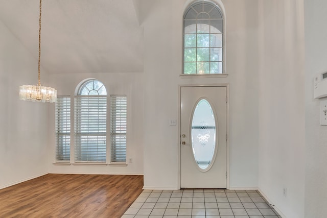 entryway featuring light tile patterned floors, high vaulted ceiling, and an inviting chandelier