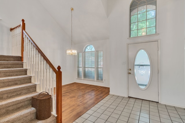 entryway with light tile patterned floors, high vaulted ceiling, and a notable chandelier