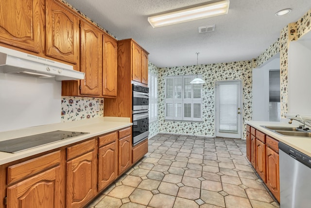 kitchen with pendant lighting, sink, stainless steel appliances, and a textured ceiling