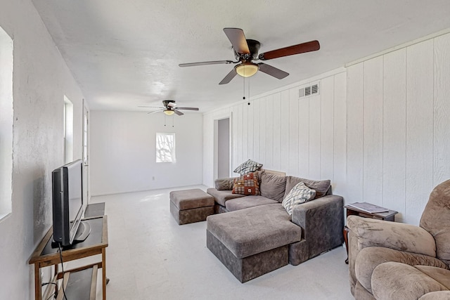 living room featuring ceiling fan and wooden walls