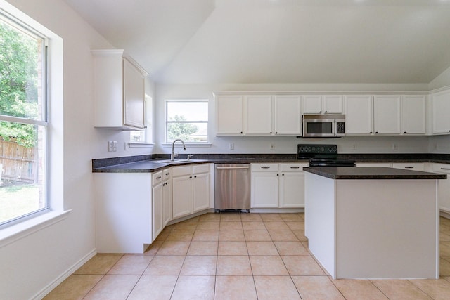 kitchen with stainless steel appliances, white cabinetry, vaulted ceiling, and sink