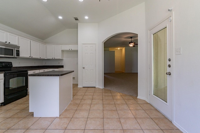 kitchen featuring light tile patterned floors, electric range, white cabinets, and a kitchen island