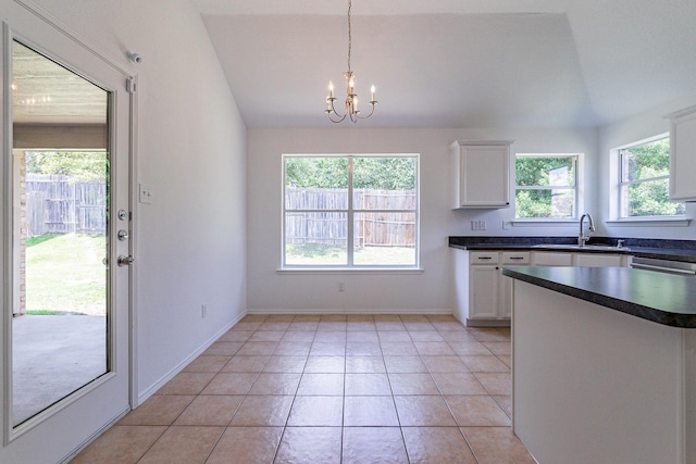 kitchen with lofted ceiling, sink, white cabinetry, decorative light fixtures, and a wealth of natural light