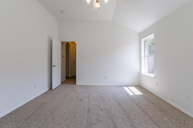 carpeted empty room with vaulted ceiling