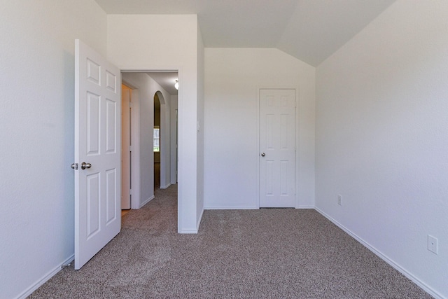 unfurnished bedroom with carpet floors and vaulted ceiling