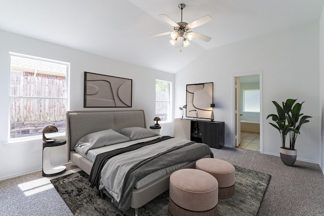 carpeted bedroom featuring ceiling fan, lofted ceiling, and ensuite bath