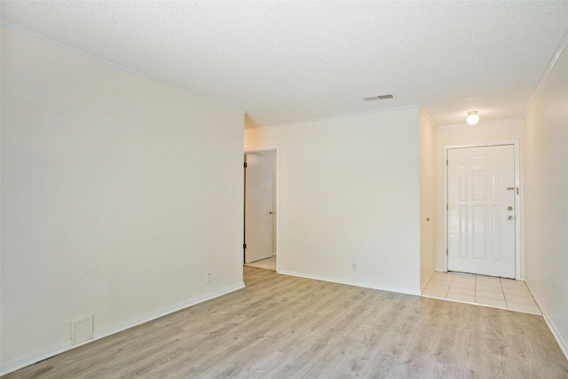 empty room with a textured ceiling, light hardwood / wood-style flooring, and ornamental molding