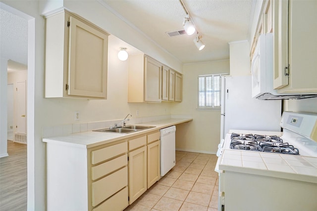 kitchen with tile countertops, white appliances, sink, light tile patterned floors, and a textured ceiling