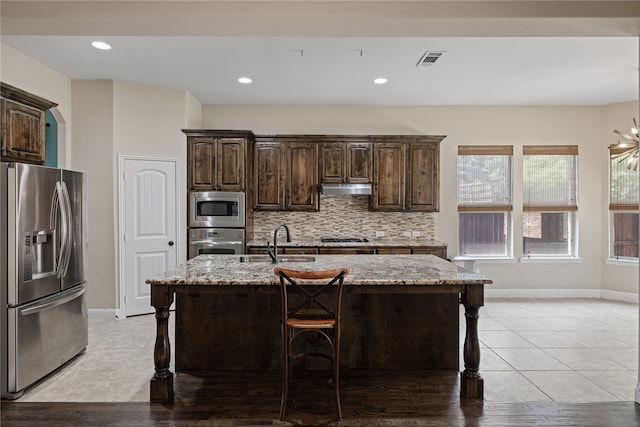 kitchen with sink, stainless steel appliances, a kitchen island with sink, and a breakfast bar area