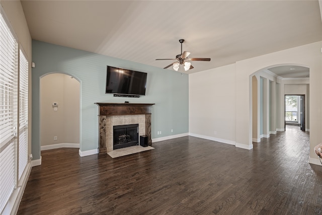 unfurnished living room featuring dark hardwood / wood-style floors, ceiling fan, and a tile fireplace