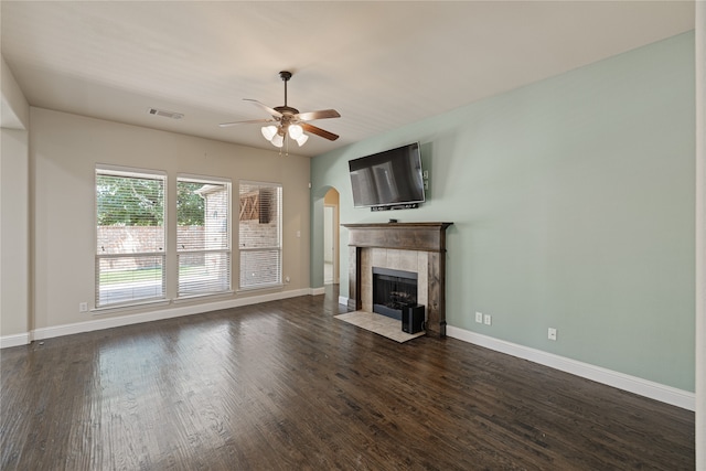 unfurnished living room with ceiling fan, dark hardwood / wood-style flooring, and a tiled fireplace