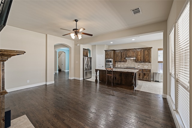 unfurnished living room featuring ceiling fan and dark hardwood / wood-style flooring