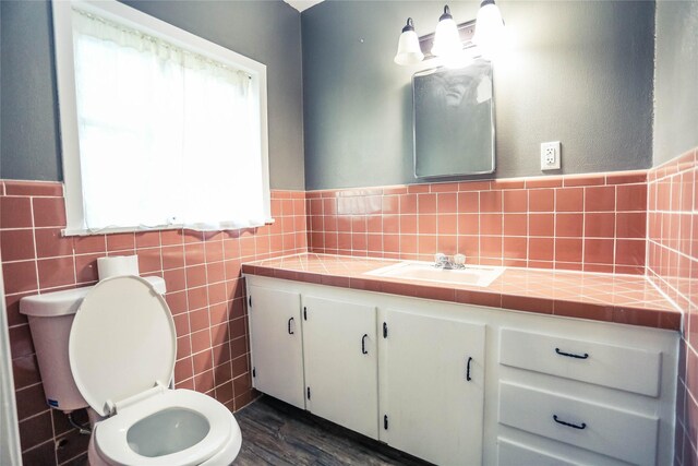 bathroom with toilet, vanity, tile walls, and hardwood / wood-style flooring