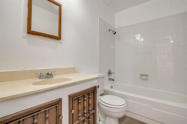 full bathroom with hardwood / wood-style floors, vanity, tiled shower / bath, and toilet