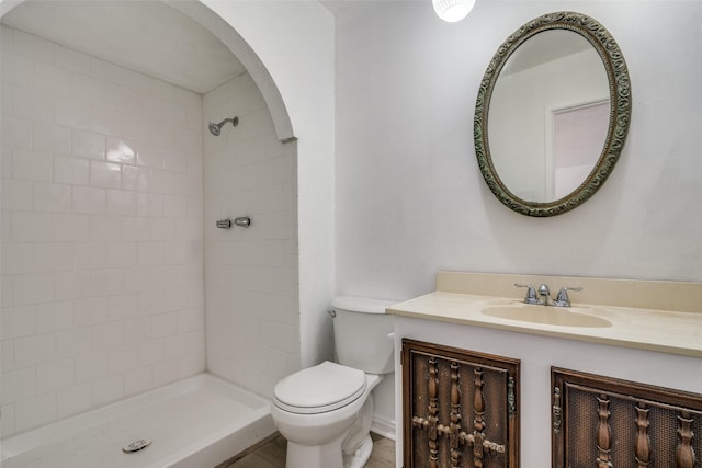 bathroom with vanity, toilet, and a tile shower