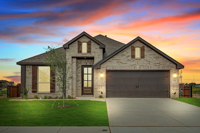 french provincial home with a lawn and a garage