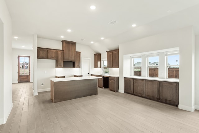 kitchen with light wood-type flooring, lofted ceiling, a center island, and a wealth of natural light