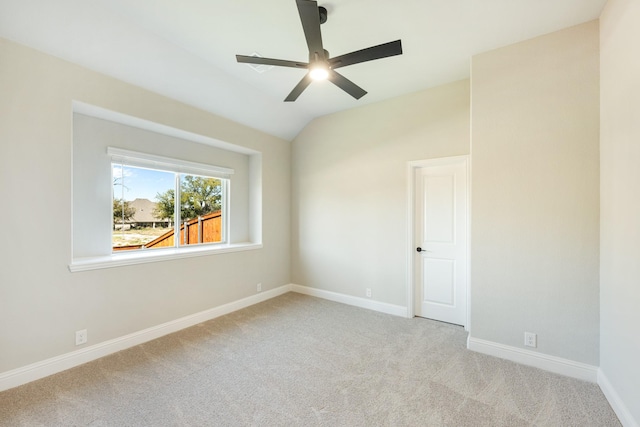 carpeted spare room with baseboards, a ceiling fan, and vaulted ceiling