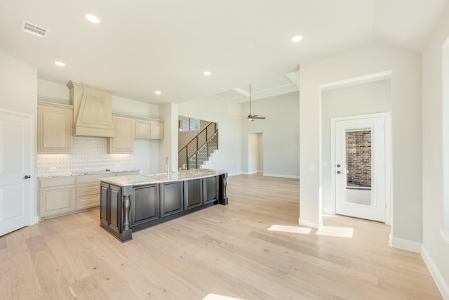 kitchen with backsplash, visible vents, cream cabinets, cooktop, and light wood finished floors