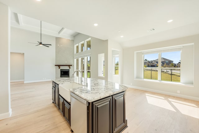 kitchen with dishwasher, light stone countertops, a fireplace, and light wood-type flooring