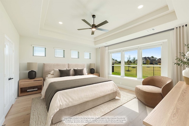 bedroom featuring a tray ceiling and light wood-type flooring