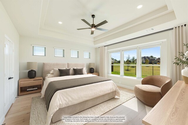 bedroom featuring light wood-style floors, recessed lighting, a raised ceiling, and multiple windows