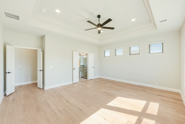 unfurnished bedroom with light hardwood / wood-style flooring, ceiling fan, and a tray ceiling