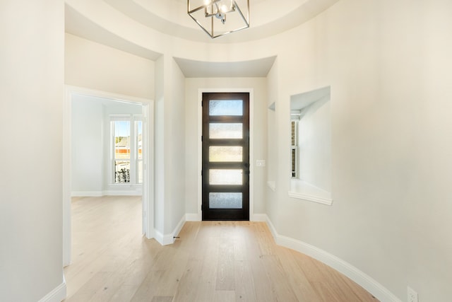 foyer featuring light hardwood / wood-style flooring, a notable chandelier, and a healthy amount of sunlight