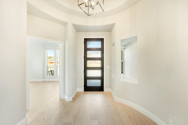 entrance foyer featuring baseboards, light wood-style flooring, and a chandelier