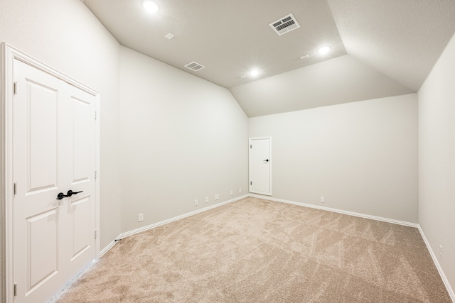 carpeted empty room with vaulted ceiling