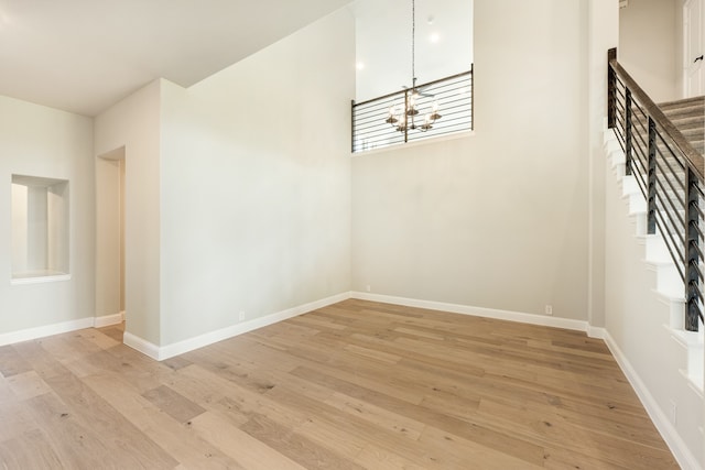 empty room with light hardwood / wood-style flooring and a chandelier