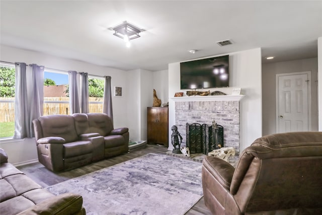 living room with a fireplace, plenty of natural light, and dark hardwood / wood-style flooring